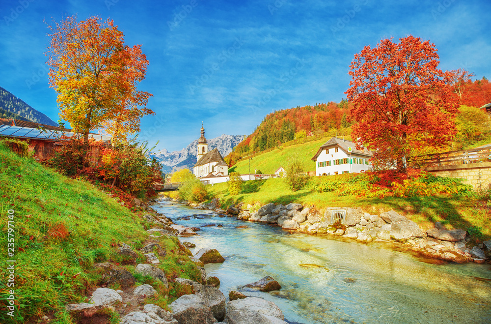 Captivating autumn scenery of Alpine river Ramsauer Ache, mountains Alps, Great view on Parish Church of St. Sebastian in Germany, Bavaria, Europe. Ramsau, Berchtesgaden National Park, German Bayern.