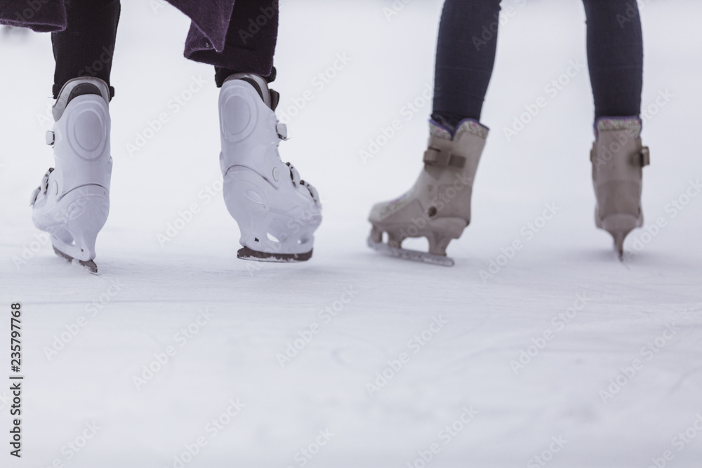 close-up of womens legs on skates in winter on an open skating rink, place for text close-up of womens legs on skates in winter on an open skating rink, place for text