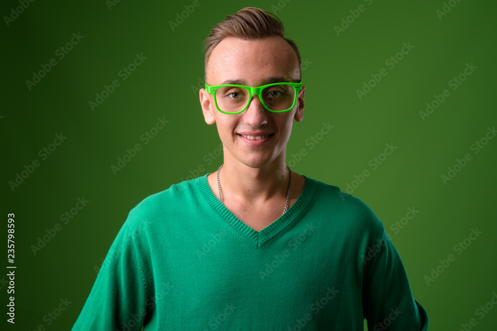 Studio shot of young handsome man against green background