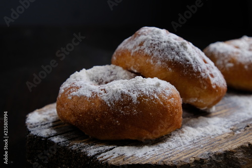 Tradition Jewish holiday sweets, donut sufganioyt with sugar powder on dark background