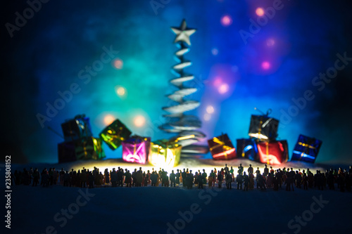 New year or Christmas holiday shopping concept. Store promotions. Silhouette of a large crowd of people watching at a big shopping trolley with gifts. People on snow prepares to shopping.