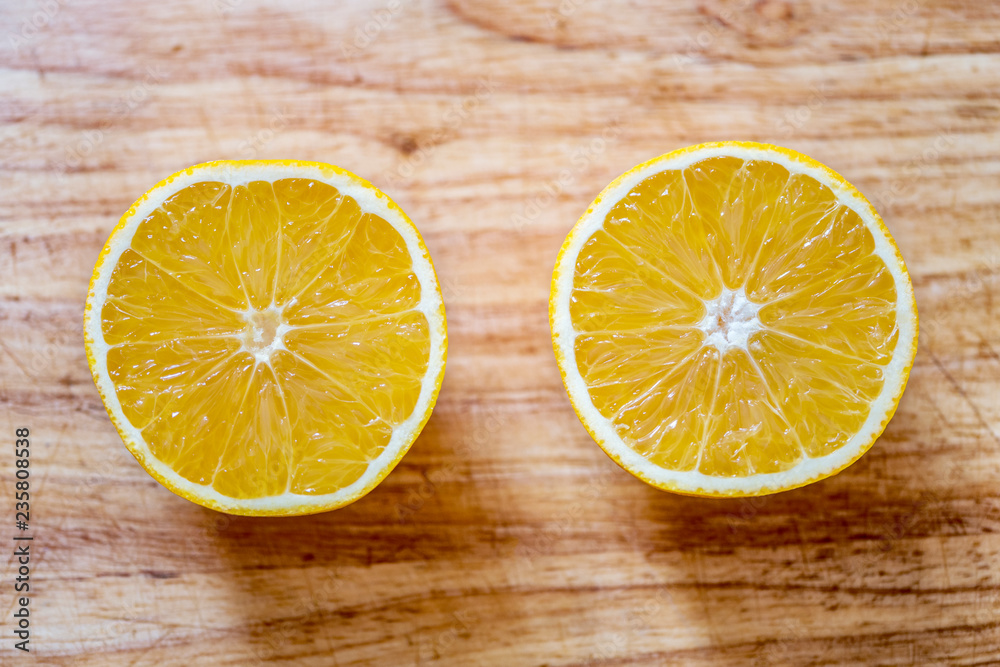Two halves of a orange on a blurred wooden board Two halves of a orange on a blurred wooden board