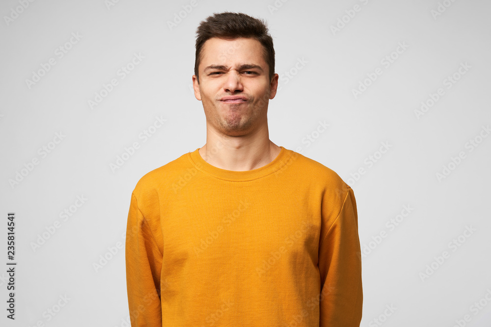 Studio shot of a young guy standing confident, chin up, on the face expression of a success, winning, show class, winner, pleased enjoying himself, isolated over white background