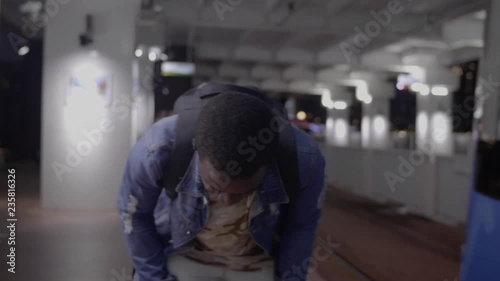 Black skin African  guy is late and runs after a departing tram on the platform in the night photo