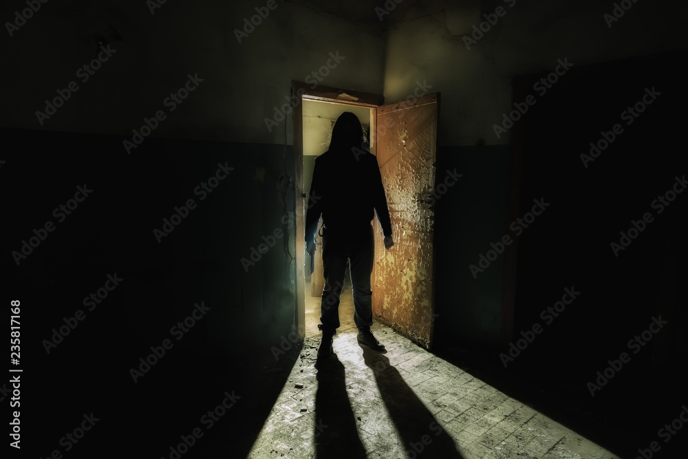 Creepy silhouette of unknown man with knife in dark abandoned building. Horror about maniac concept Creepy silhouette of unknown man with knife in dark abandoned building. Horror about maniac concept