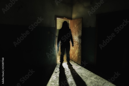 Foto Creepy silhouette of unknown man with knife in dark abandoned building
