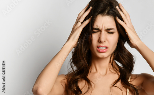 Woman with closed eyes suffering from headache touching her temples feeling stress