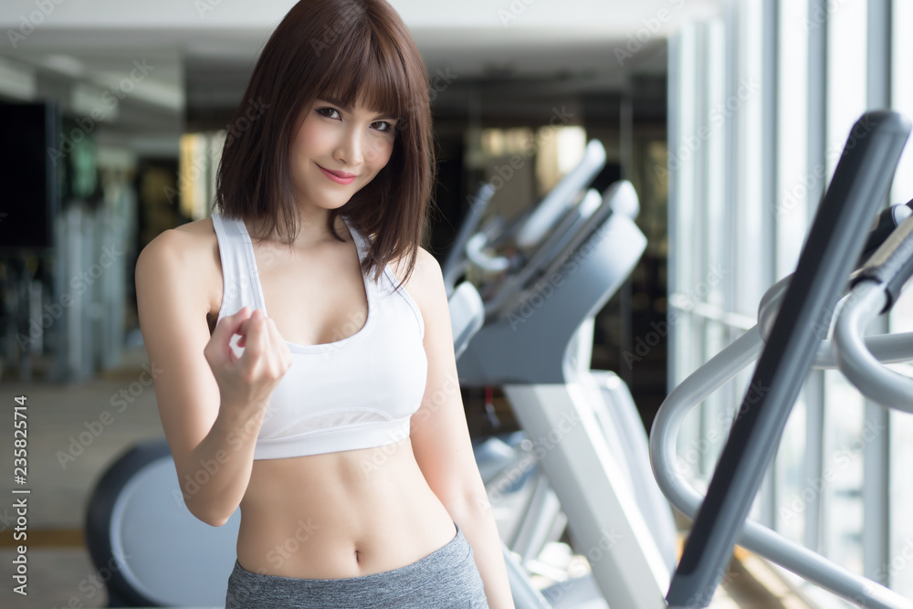 healthy strong fitness woman looking and pointing at you. portrait of fitness woman in gym posing for gym workout, looking and pointing to invite you to join the club. asian adult fitness woman model healthy strong fitness woman looking and pointing at you. portrait of fitness woman in gym posing for gym workout, looking and pointing to invite you to join the club. asian adult fitness woman model