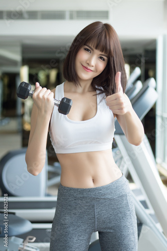 healthy strong fitness woman looking and pointing at you. portrait of fitness woman in gym posing for gym workout, looking and pointing to invite you to join the club. asian adult fitness woman model