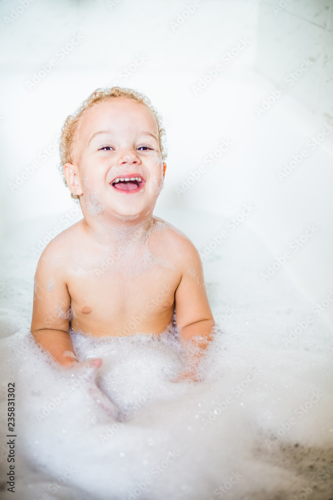 Cute two year old boy taking a relaxing bath with foam Cute two year old boy taking a relaxing bath with foam
