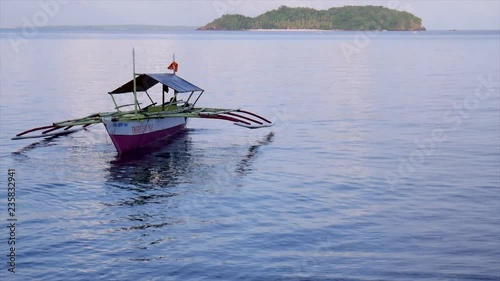 Outrigger boat at dusk off of Biliran Island, Philippines, with Dalutan Island in the background. photo