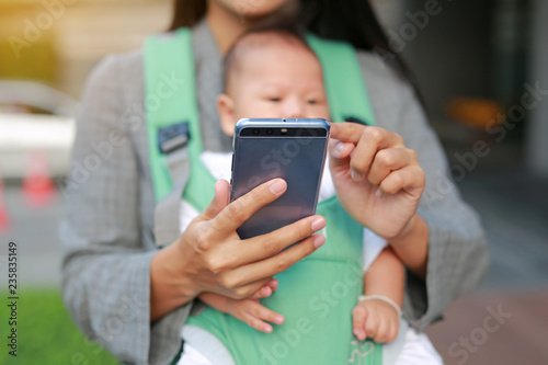 Close up business woman working by telephone with carrying her infant.