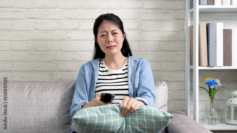 Obraz premium Sad young woman watching television and crying.