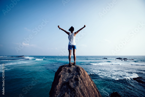 Schilderij op canvas Freedom young woman outstretched arms on seaside rock cliff edge
