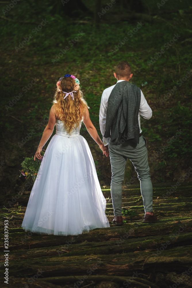 Newlyweds holding their hands during the walk in a forest
