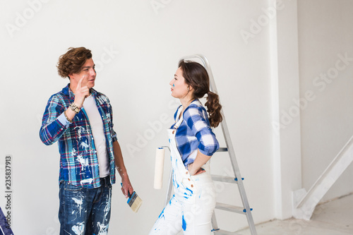 People, renovation and repair concept - Young woman and man discussing new apartment