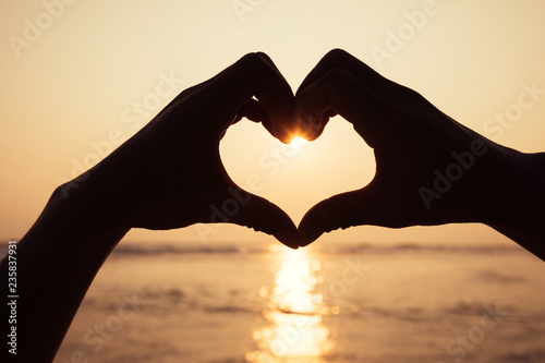 Sunset shining through heart shaped hands