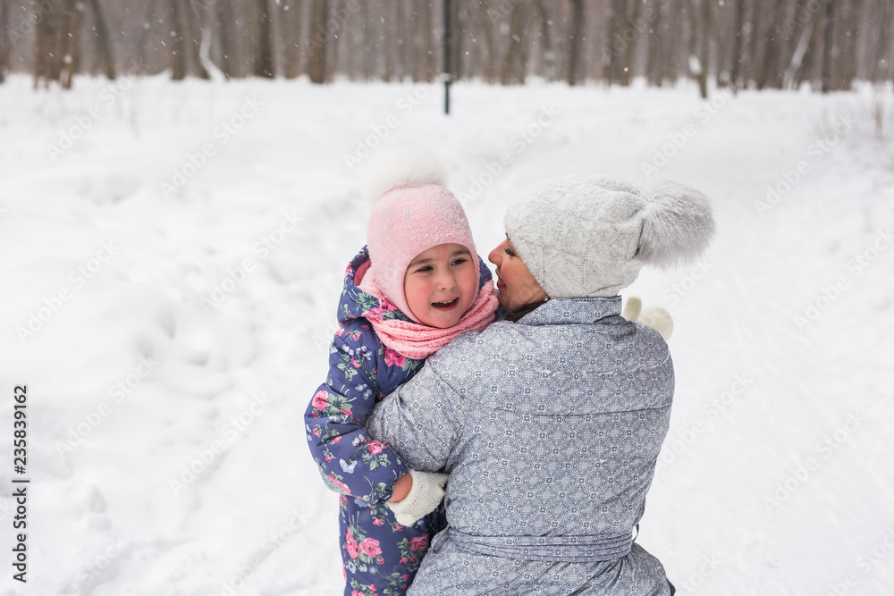 Family, children and nature concept - Young mother hug little happy child in the winter park Family, children and nature concept - Young mother hug little happy child in the winter park