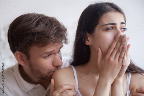 Loving man soothing crying woman with handkerchief in hands, apologizing after quarrel, interruption unwanted pregnancy, miscarriage, boyfriend kiss girlfriend shoulder, hug support, break up close up