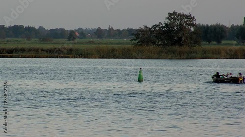 small boat sails in evening next to bouy photo