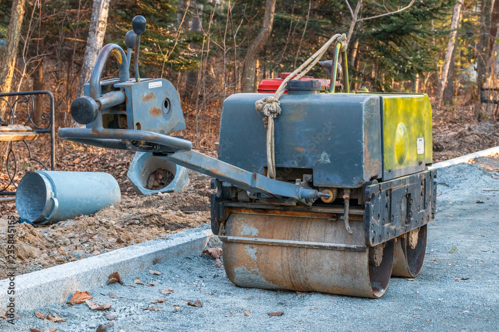 Manual compact asphalt roller for tamping soil at a construction site Manual compact asphalt roller for tamping soil at a construction site