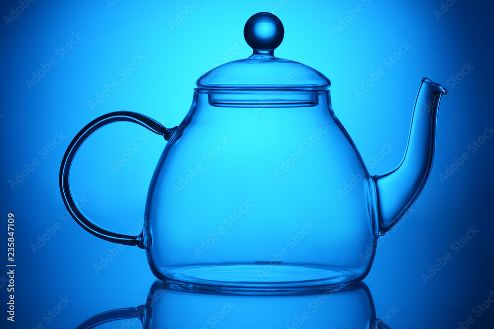 Fototapeta premium Transparent glass teapot on blue