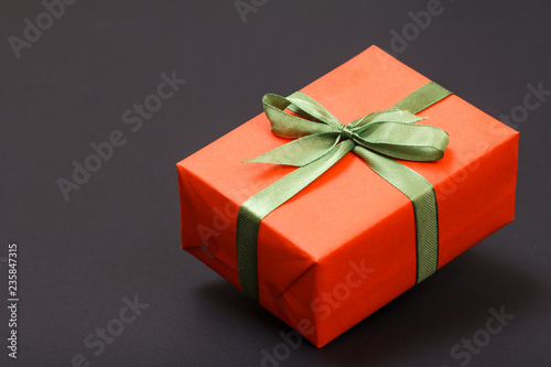 Gift box tied with ribbon on black background.