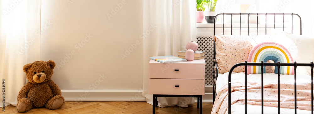 Fototapeta Zabawka pluszowa na białej ścianie z miejsca do kopiowania we wnętrzu sypialni dziecka z łóżkiem. Prawdziwe zdjęcie