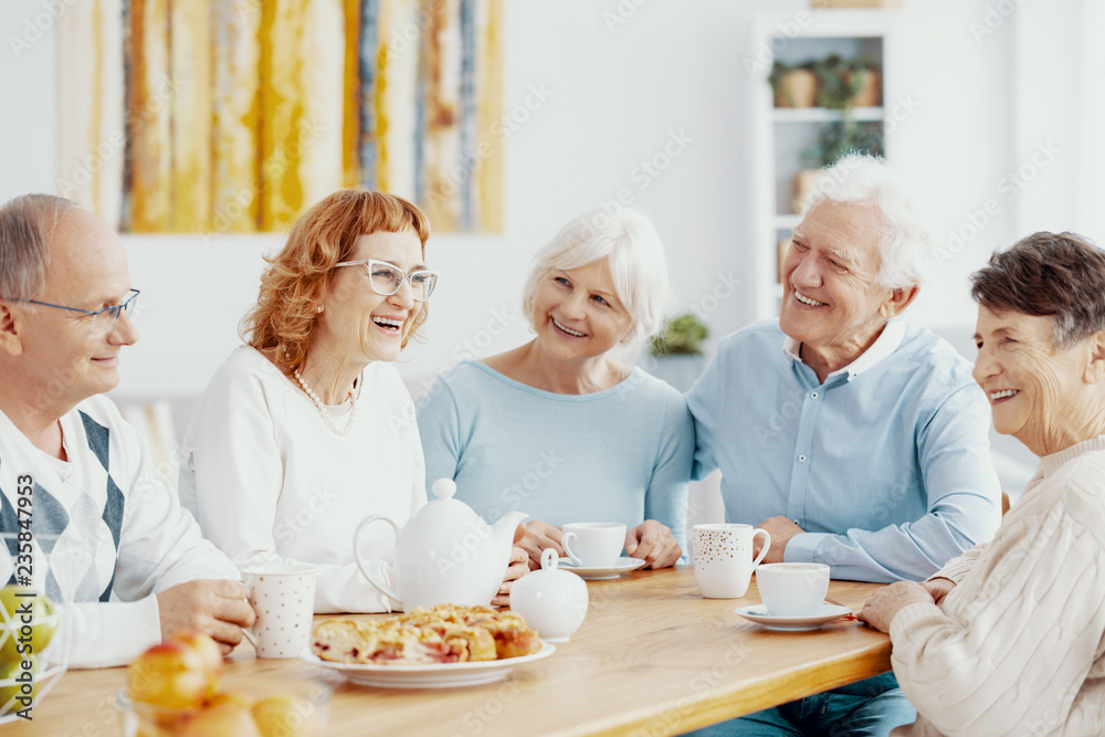 Group of happy older people laughing together on a coffee meeting at nursing home