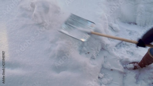 Woman cleans snow near the house.