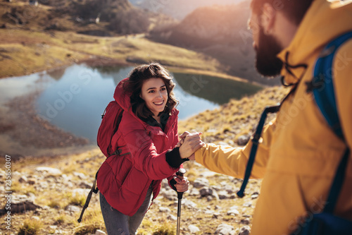Fotografija Helping hand - hiker woman getting help on hike happy overcoming obstacle