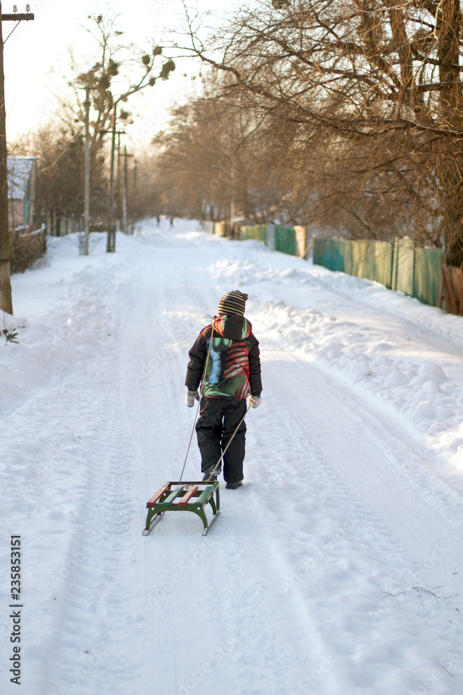 Little boy is carrying sleigh