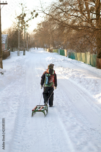 Little boy is carrying sleigh