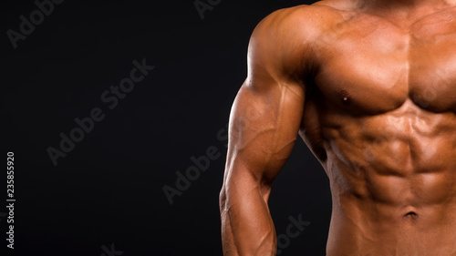 Low-key image of muscular masculine man over dark background photo
