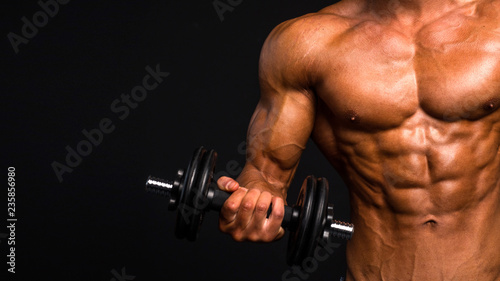 close up image of naked sportsman raising his hand with dumbell. controling musculars