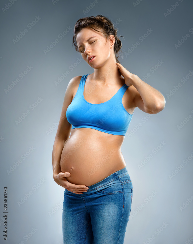 Pregnant woman suffering from neck pain on gray background. Medical concept. Pregnant woman suffering from neck pain on gray background. Medical concept.