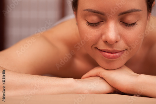 Closeup of a happy beautiful healthy woman smiling, relaxing at spa center. Young attractive woman with flawless smooth skin enjoying spa treatment. Recreation, rejuvenation and pampering concept