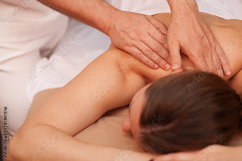 Unrecognizable woman receiving back massage from a professional masseur at the beauty clinic. Spa therapist massaging back of female client. Woman enjoying therapeutic body massage. Skincare  health