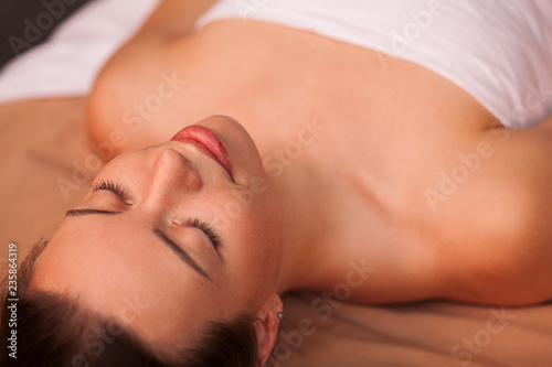 Cropped close up of a gorgeous happy woman with flawless skin smiling joyfully, resting at spa center after receiving massage. Attractive female relaxing at pampering salon. Beauty, leisure concept