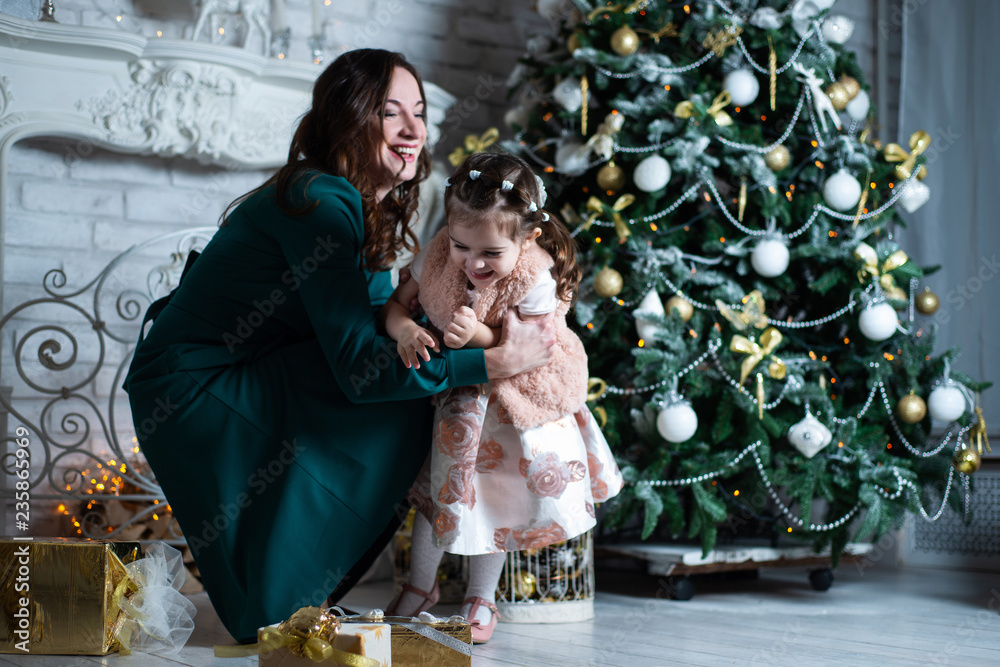 Obraz premium Merry Christmas and happy holidays. Mother and daughter having fun near the Christmas tree with gifts