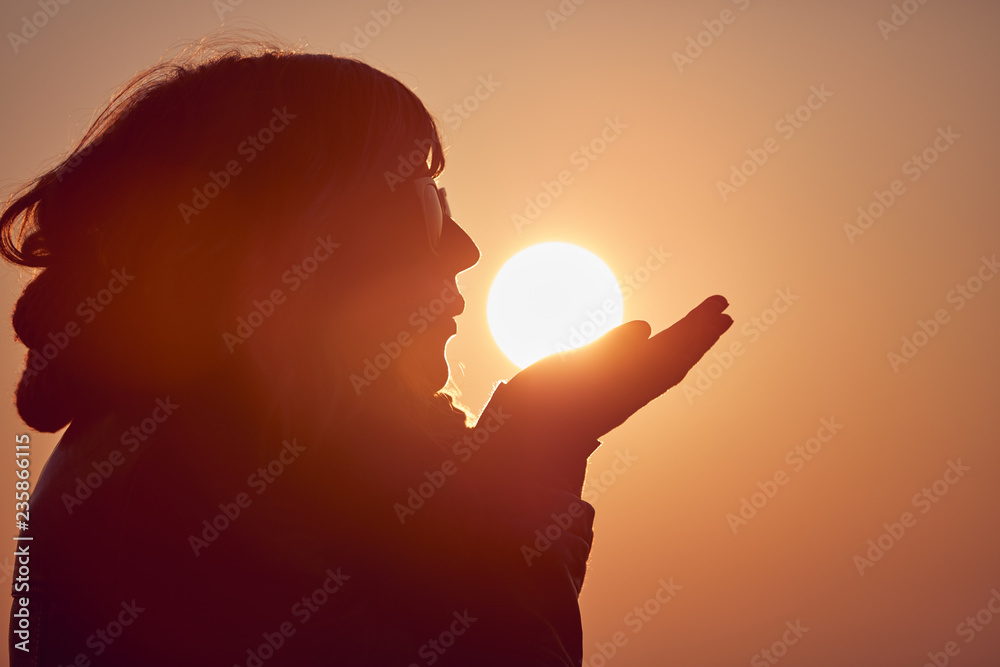 Naklejka premium Woman with praying arms enjoying the sunrise / sunset time.
