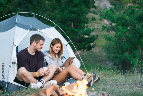Smiling young couple using tablet computer on a camping 