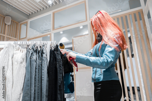 Canvas Print red hair young girl in a blue leather jacket chooses pants for sale