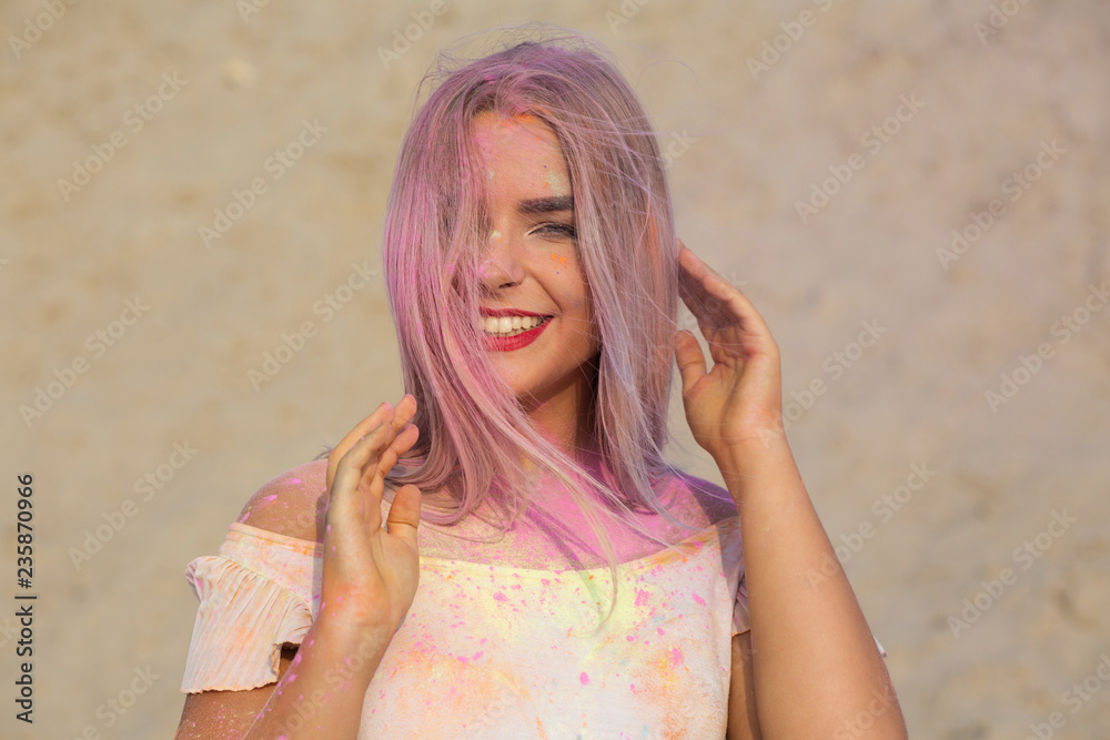 Closeup shot of expressive blonde model with red lipstick covered with pink dry paint Holi at the desert Closeup shot of expressive blonde model with red lipstick covered with pink dry paint Holi at the desert