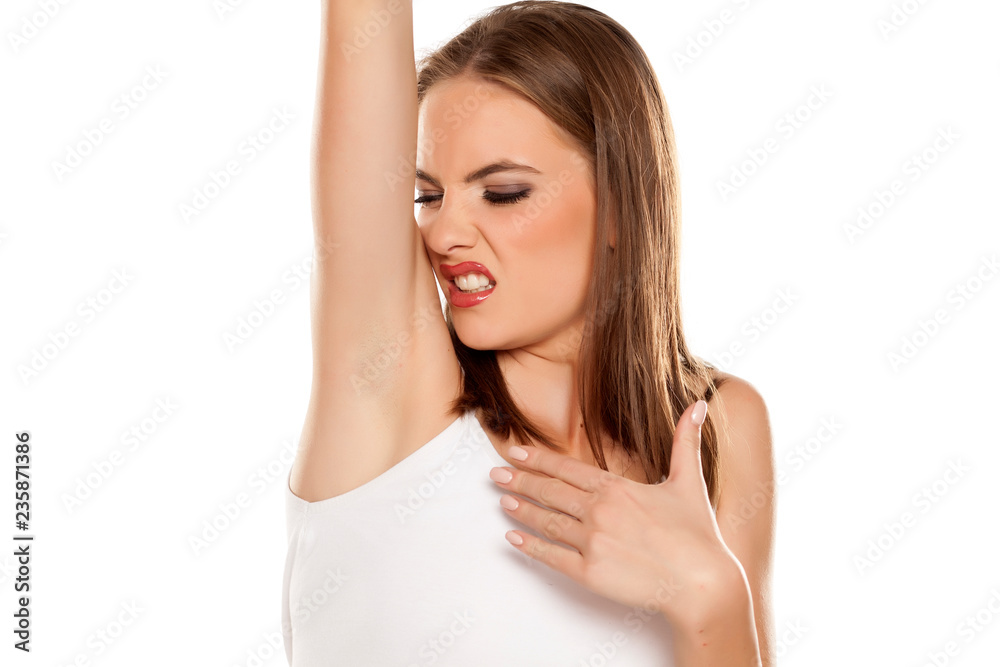 Beautiful girl smelling her armpit on white background Beautiful girl smelling her armpit on white background