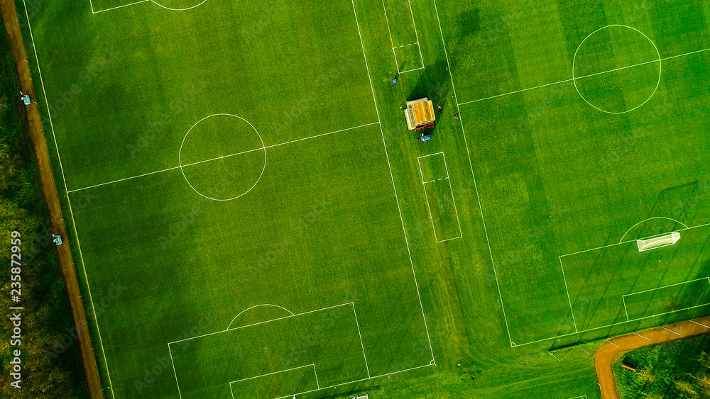 Aerial image over artificial grass football pitches. Long shadows thrown by a low sun. - obrazy, fototapety, plakaty 