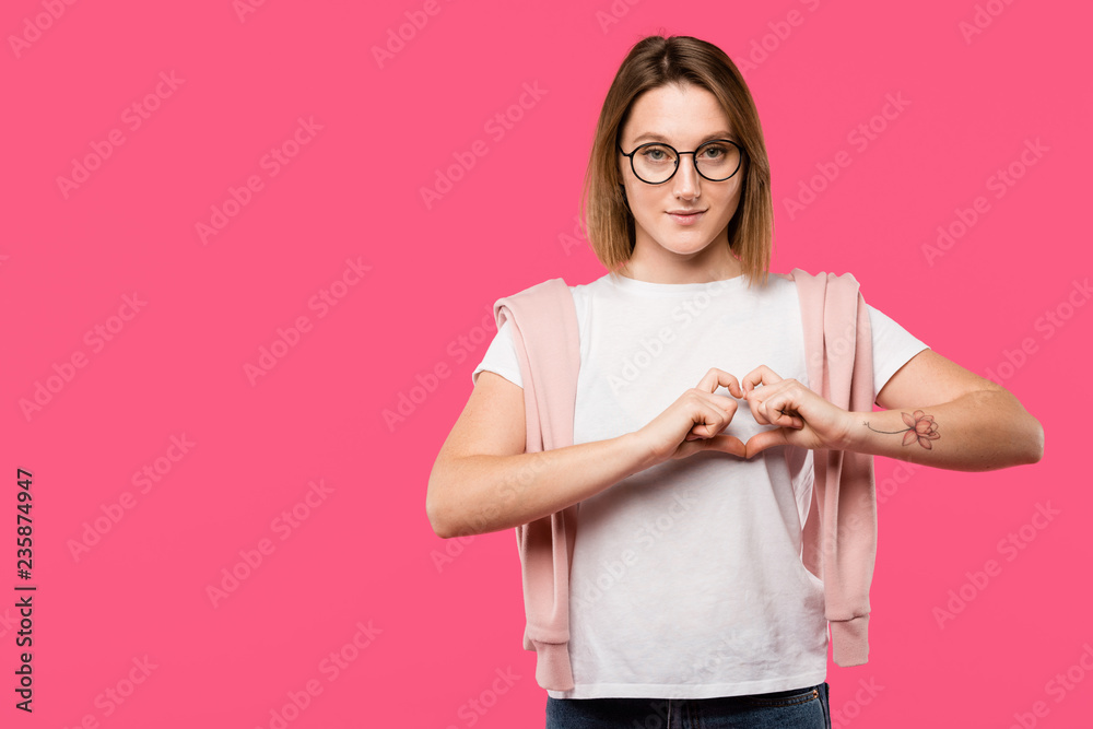 stylish girl in eyeglasses showing heart symbol isolated on pink stylish girl in eyeglasses showing heart symbol isolated on pink