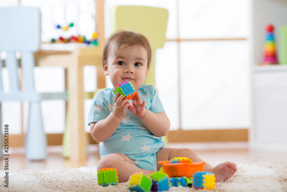 Baby boy playing with colorful plastic bricks on the carpet on floor. Toddler having fun and building out of constructor bricks. Early learning and developing toys concepts Baby boy playing with colorful plastic bricks on the carpet on floor. Toddler having fun and building out of constructor bricks. Early learning and developing toys concepts