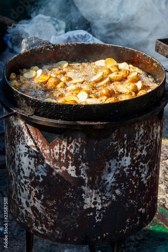Roasted potatoes cooking in cast-iron frying pan outdoors