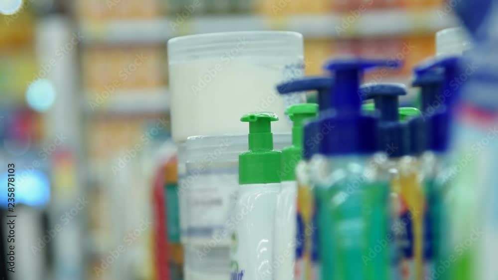 Close-up shot of a woman in the store taking from the shelf a cream tub. Shopping in the deparment of body care and cosmetics Close-up shot of a woman in the store taking from the shelf a cream tub. Shopping in the deparment of body care and cosmetics